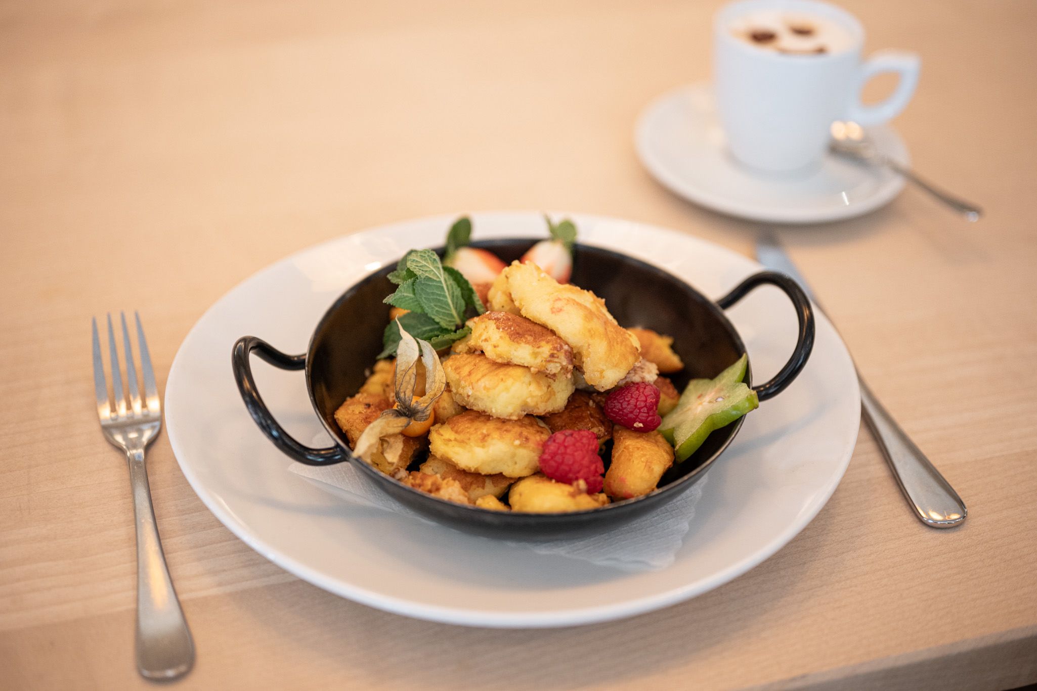 Kaiserschmarrn mit frischen Beeren, liebevoll serviert in einer kleinen Pfanne.
