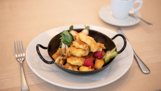 Kaiserschmarrn mit frischen Beeren, liebevoll serviert in einer kleinen Pfanne.