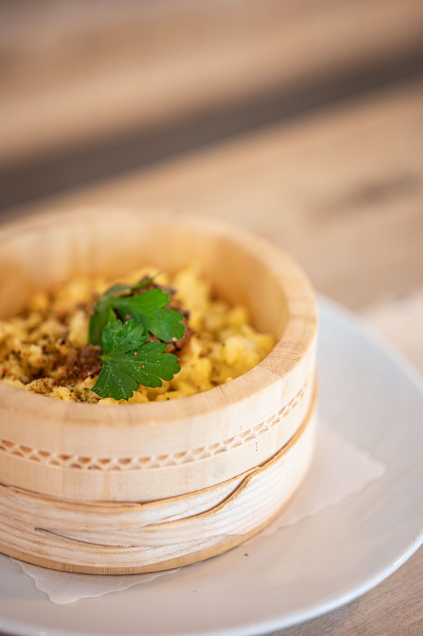 Eierspätzle mit Röstzwiebeln und Petersilie in einem runden Holzschälchen serviert.