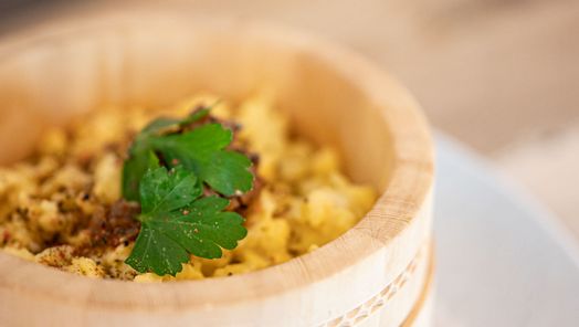 Eierspätzle mit Röstzwiebeln und Petersilie in einem runden Holzschälchen serviert.