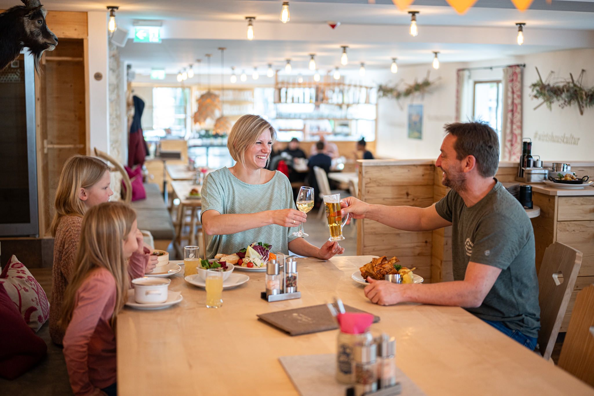 Fröhliche Familie beim Essen und Anstoßen in der gemütlichen Stube.