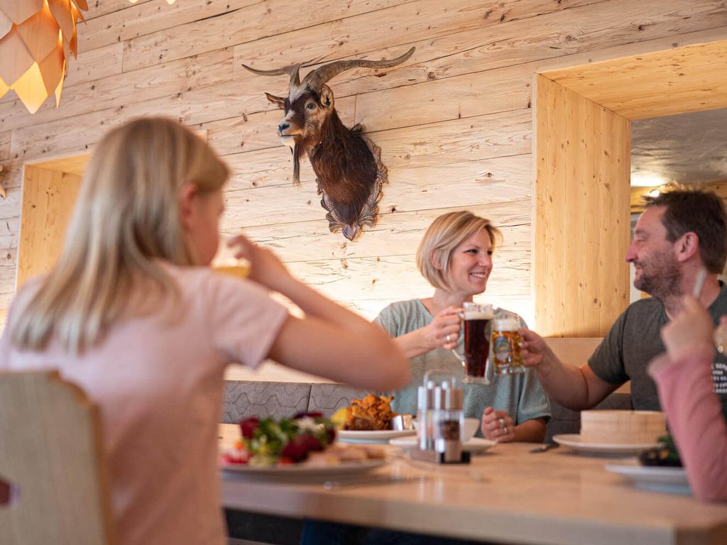 Drei Gäste sitzen in einer gemütlichen Atmosphäre am Tisch, trinken und Essen zusammen.