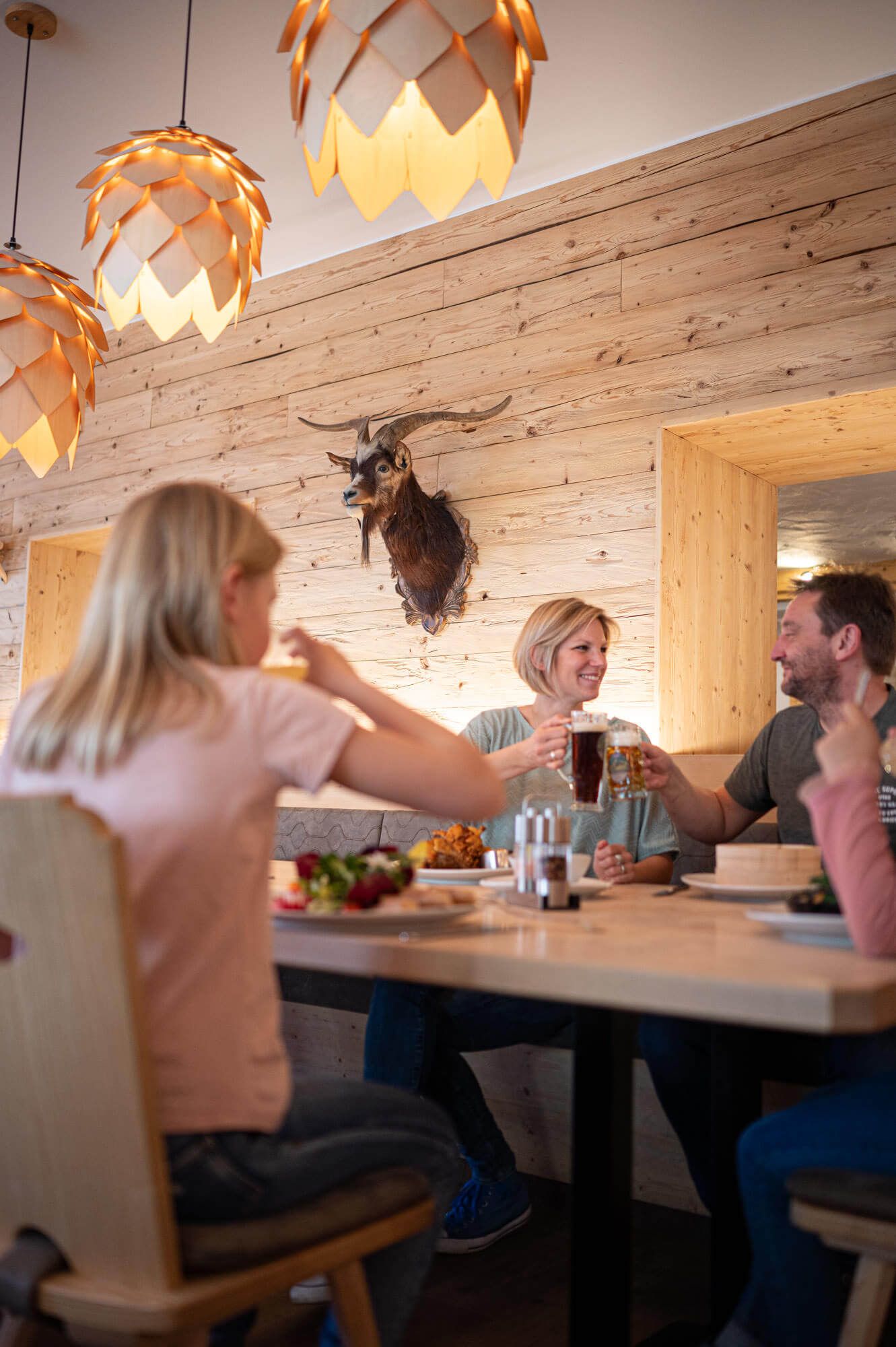 Drei Gäste sitzen in einer gemütlichen Atmosphäre am Tisch, trinken und Essen zusammen.