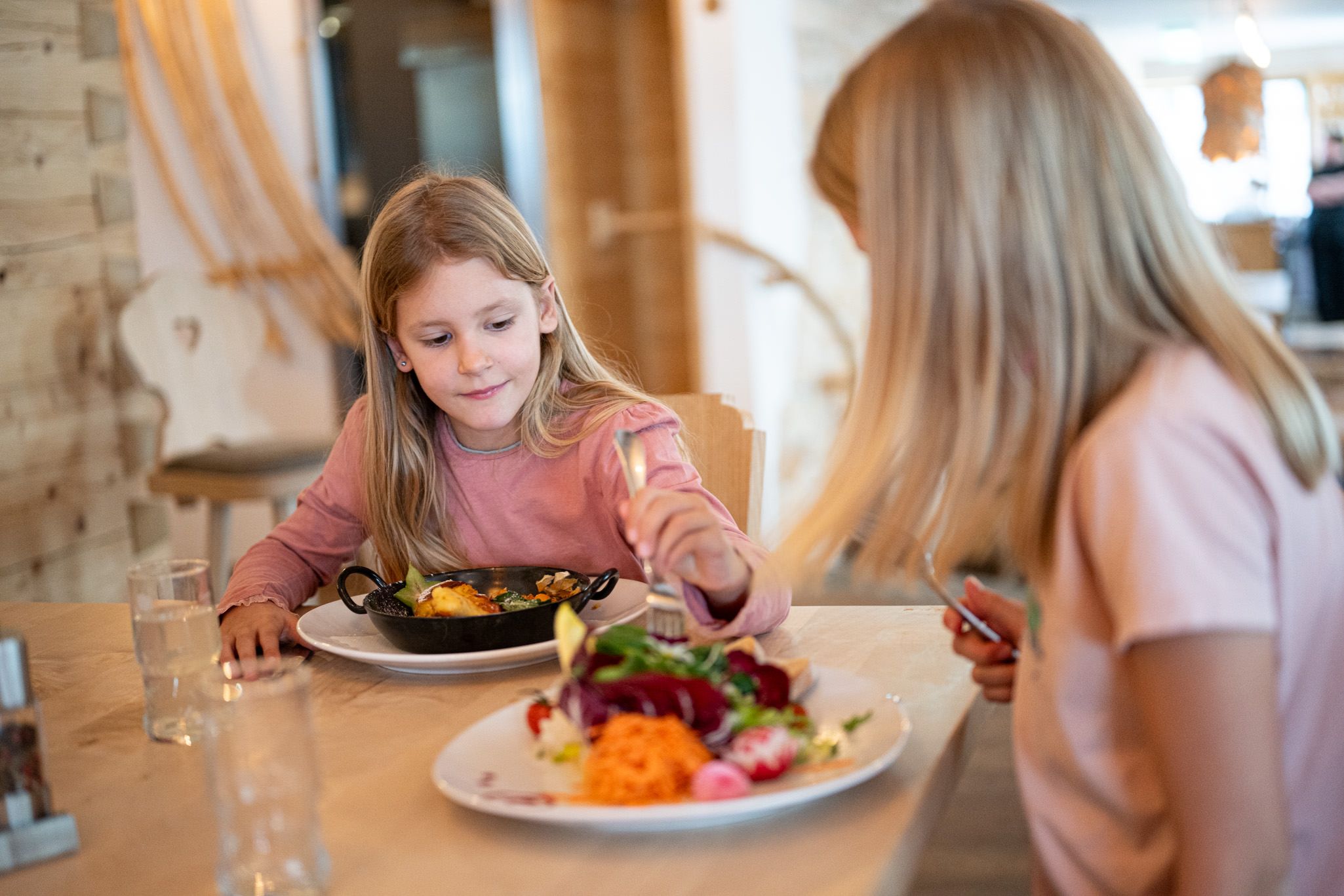 Zwei Mädchen genießen ihr Essen am liebevoll gedeckten Tisch.