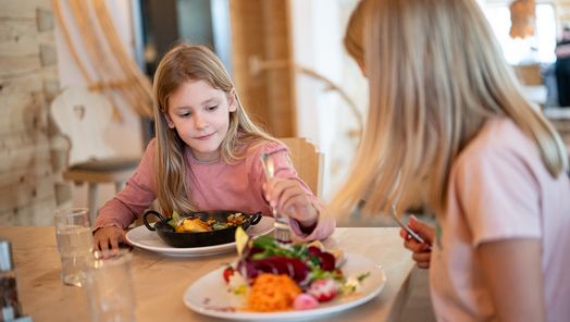 Zwei Mädchen genießen ihr Essen am liebevoll gedeckten Tisch.