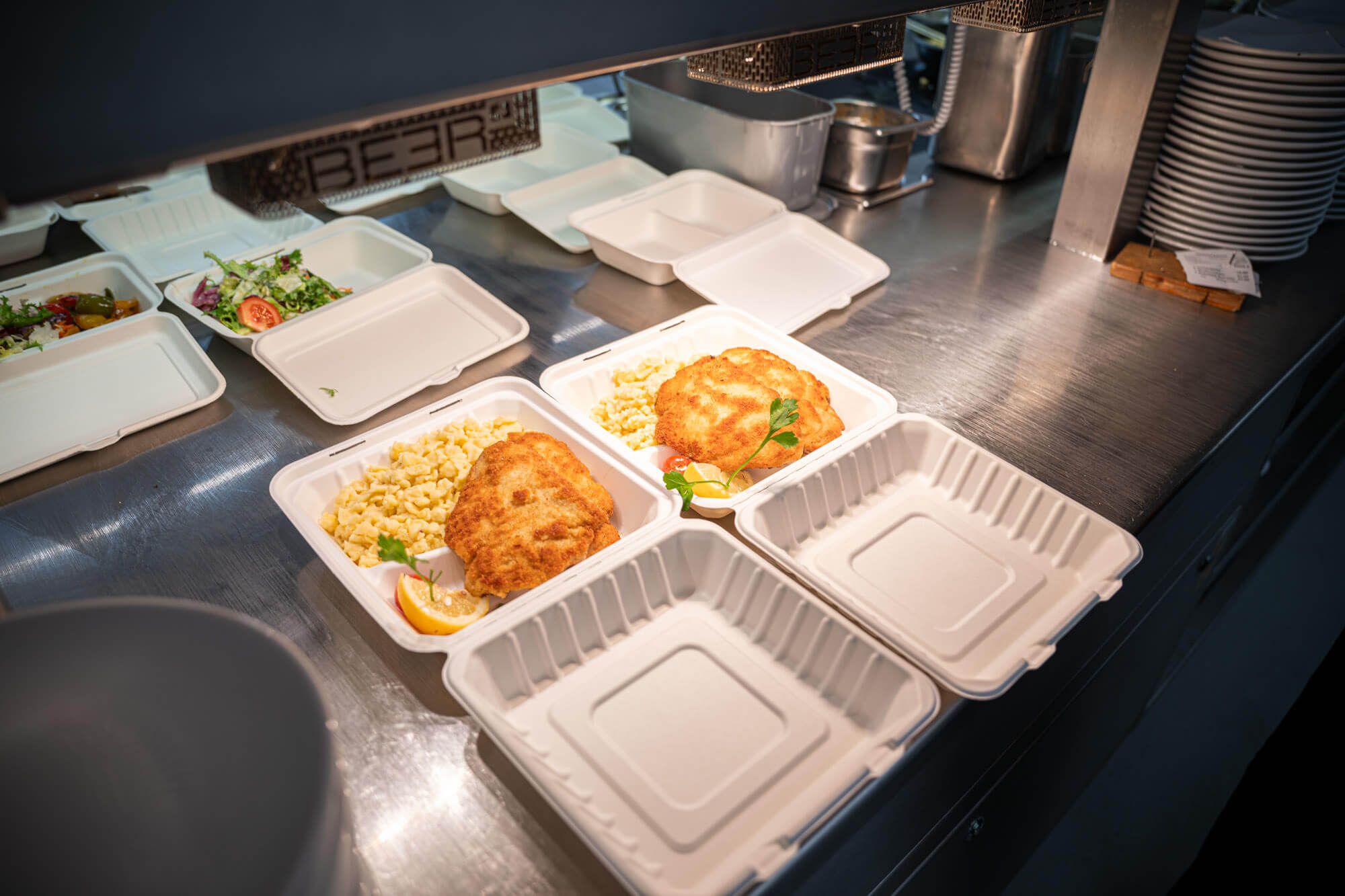 Frisch zubereitetes Schnitzel mit Spätzle, angerichtet in Schalen zum Mitnehmen.