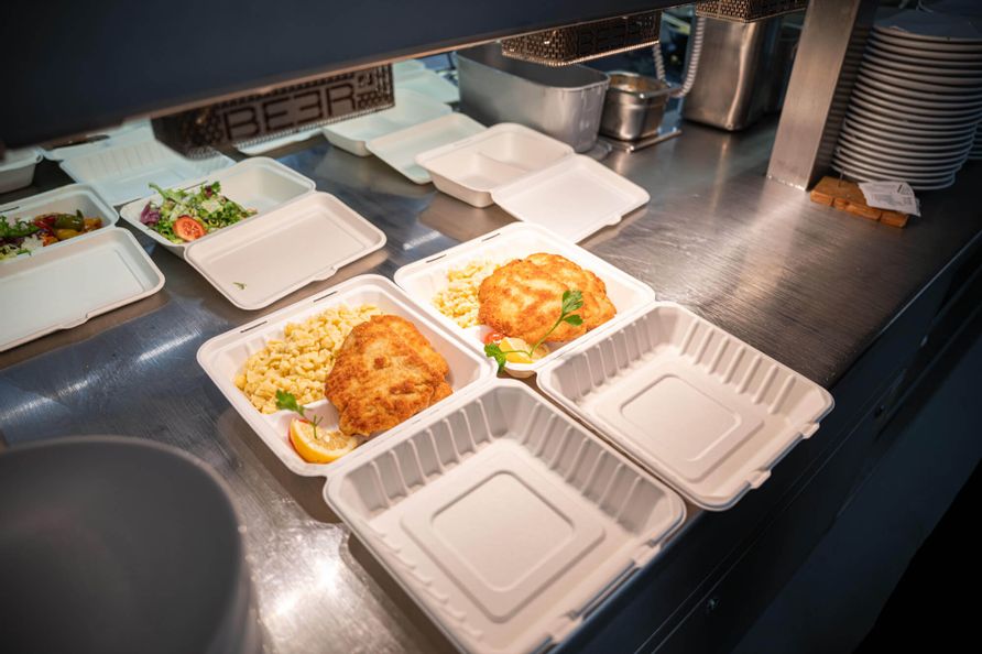 Frisch zubereitetes Schnitzel mit Spätzle, angerichtet in Schalen zum Mitnehmen.
