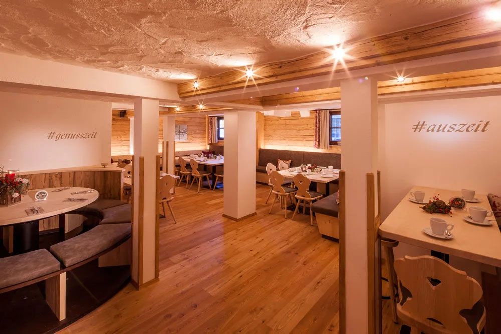 Gemütliche Stube mit hellem Holz und eingedeckten Tischen.