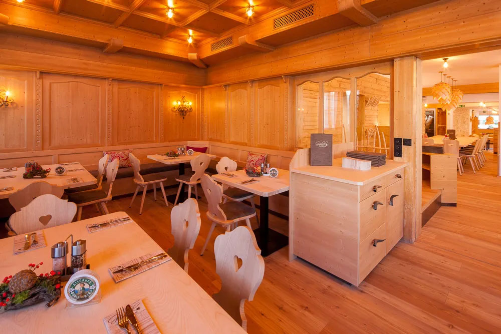 Gemütliche Gaststube in hellem Holz mit liebevoll gedeckten Tischen und traditionellem Charme.