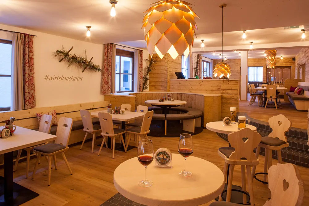 Einladender Gastraum im Alpenstil mit Herzstühlen, Holzdecke und liebevoll gedeckten Plätzen