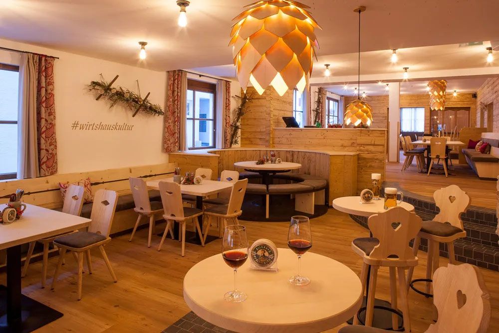 Einladender Gastraum im Alpenstil mit Herzstühlen, Holzdecke und liebevoll gedeckten Plätzen