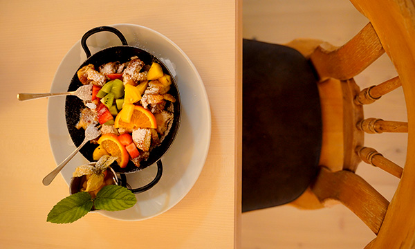 Kaiserschmarrn mit frischen Früchten und Puderzucker in einer kleinen Pfanne serviert.