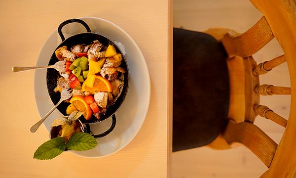 Kaiserschmarrn mit frischen Früchten und Puderzucker in einer kleinen Pfanne serviert.