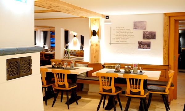 Heller Gastraum mit Holztischen, Stühlen und liebevoll gedeckten Tafeln.