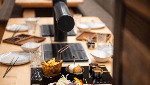 Ein liebevoll gedeckter Tisch mit eingebautem Grill, frischen Grillzutaten, Saucen, Pommes und Ofenkartoffel – bereit für ein gemütliches Grillvergnügen in der Grillstube.